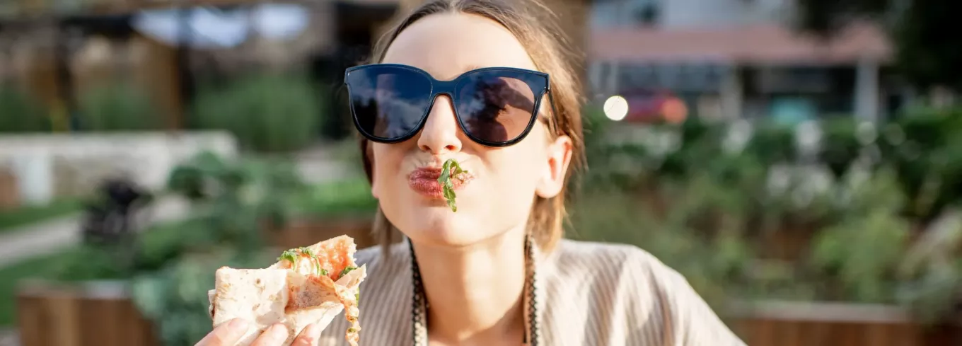 Frau genießt Essen geliefert von Lieferando & bezahlt mit Pluxee Gutscheinen 