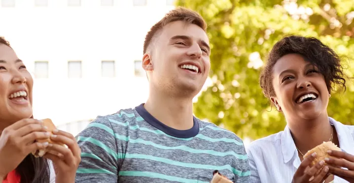 Team lacht mit Essen in der Hand | Pluxee