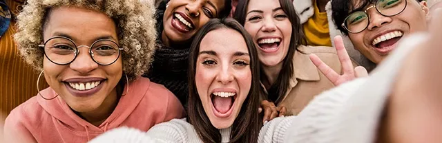Eine fröhliche Gruppe von Menschen macht gemeinsam ein Selfie. Alle lächeln und zeigen positive Gesten. Die Szene vermittelt Teamgeist, Motivation und Zusammenhalt.